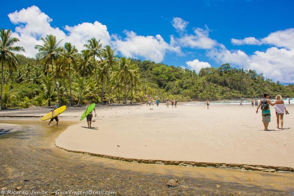 Imagem de dois surfistas com pranchas coloridas na Praia da Engenhoca.